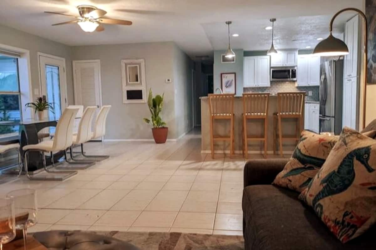 Open-plan living, dining, and kitchen area of a vacation rental with tile floors and breakfast bar seating