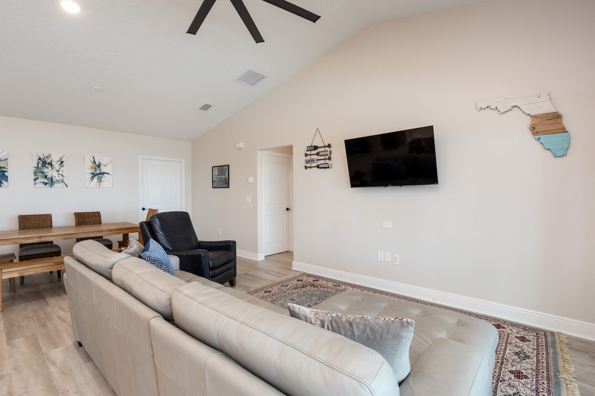 Spacious living room with large sectional sofa, wall-mounted TV and vaulted ceiling