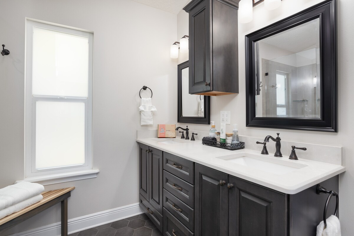 Bathroom with dark dual-sink vanity, framed mirrors and fresh towels