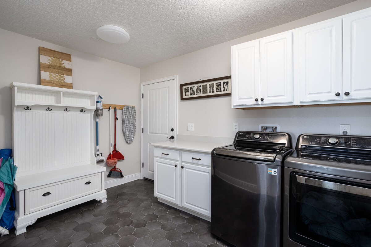 Laundry room with full-size washer and dryer, white cabinets and a mudroom bench