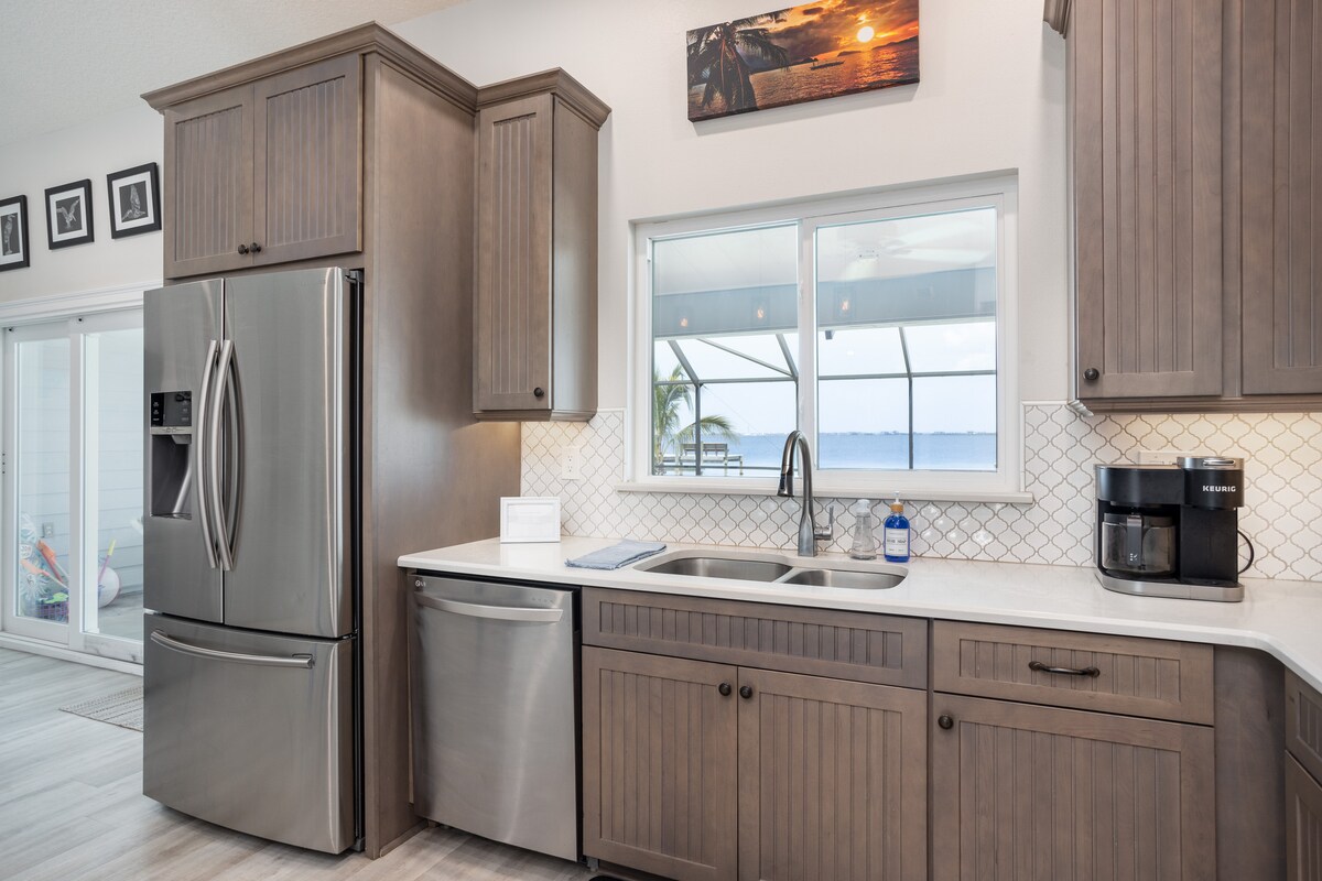 Kitchen with stainless refrigerator, coffee station and a window view of the water